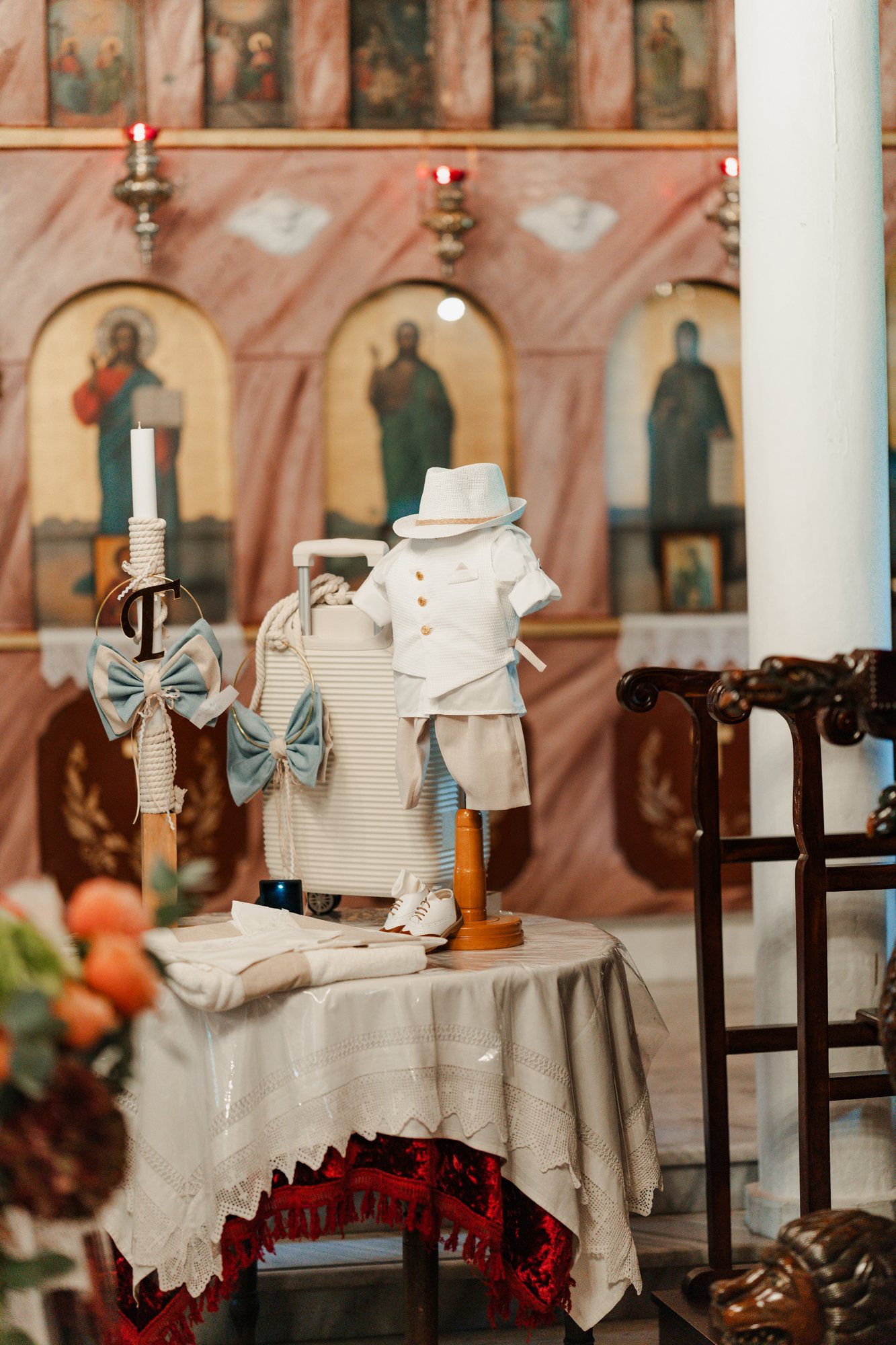 The christening outfit and candle in front of the church icons