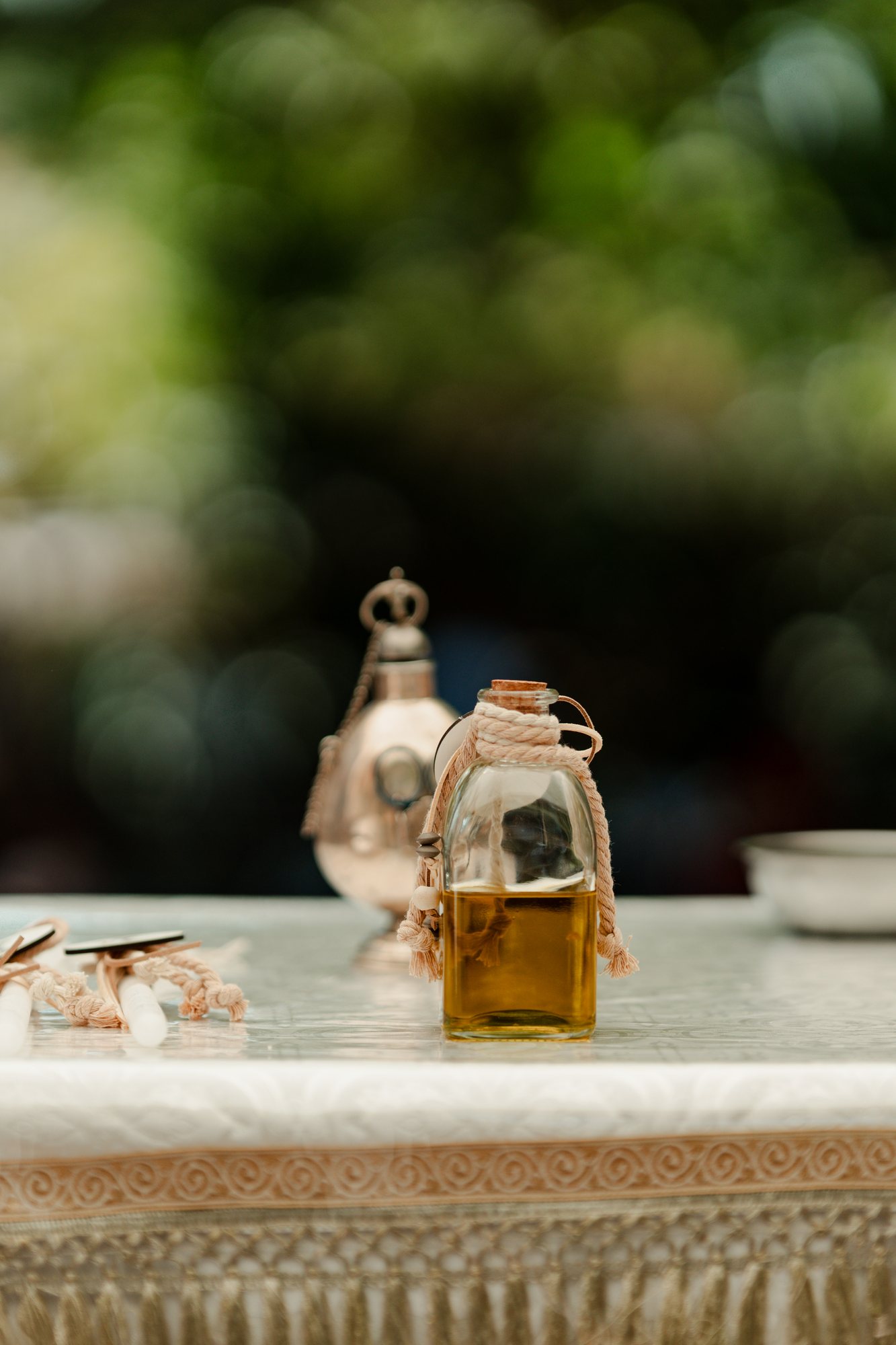The oil bottle beside a silver jug on a lace tablecloth