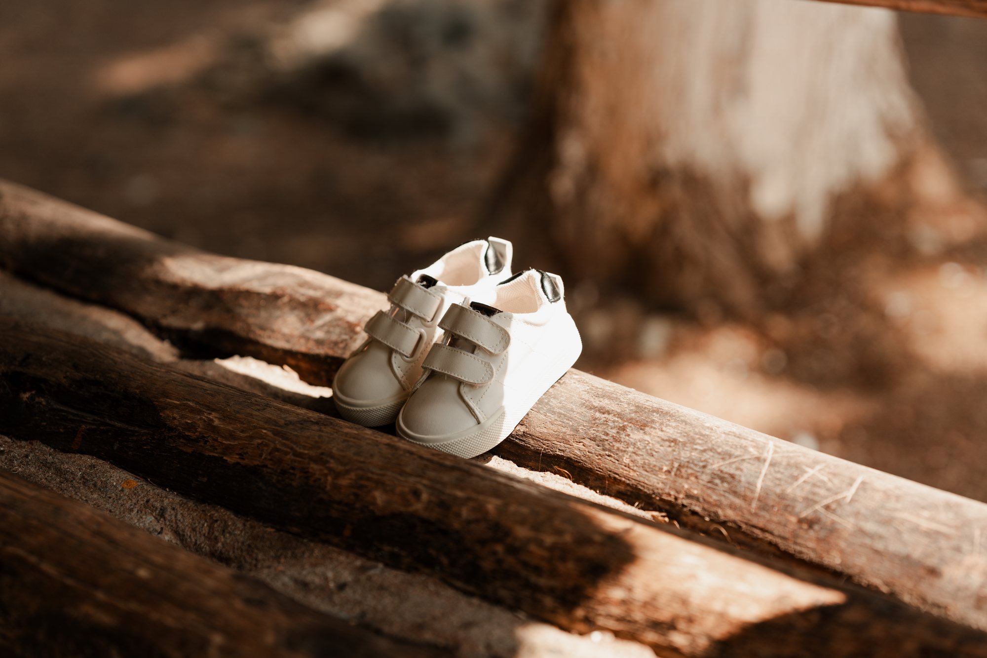 White baby shoes resting on a wooden log
