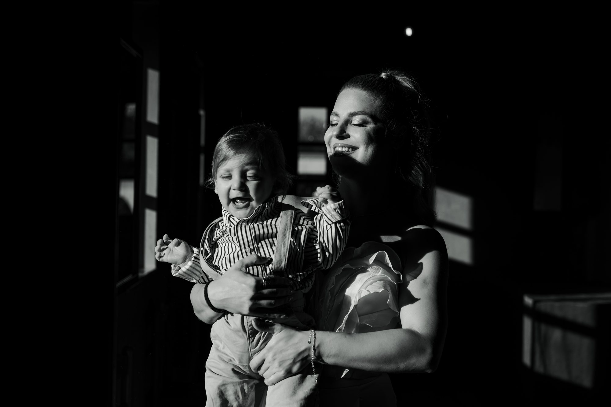 Black and white photo of a mother laughing with her child in her arms