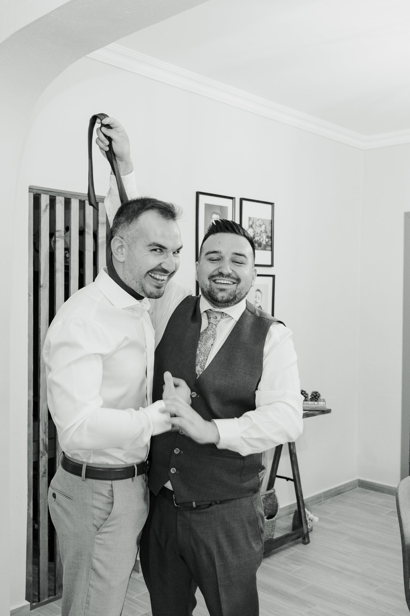 Black and white photo of the groom and a friend laughing together