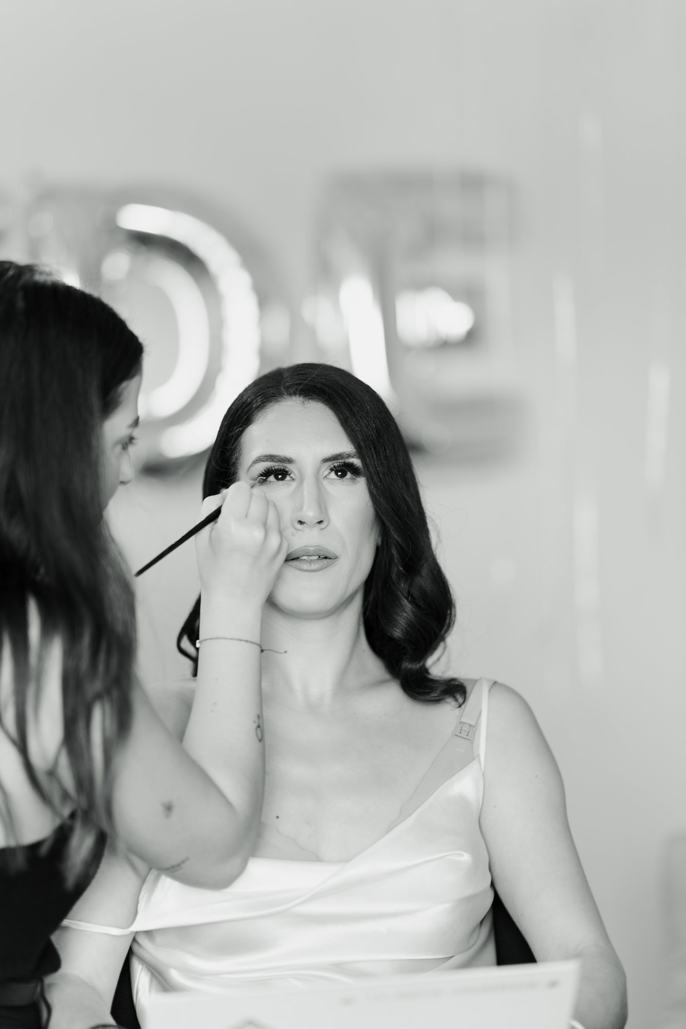 Black and white photo of the bride having her eye make-up done