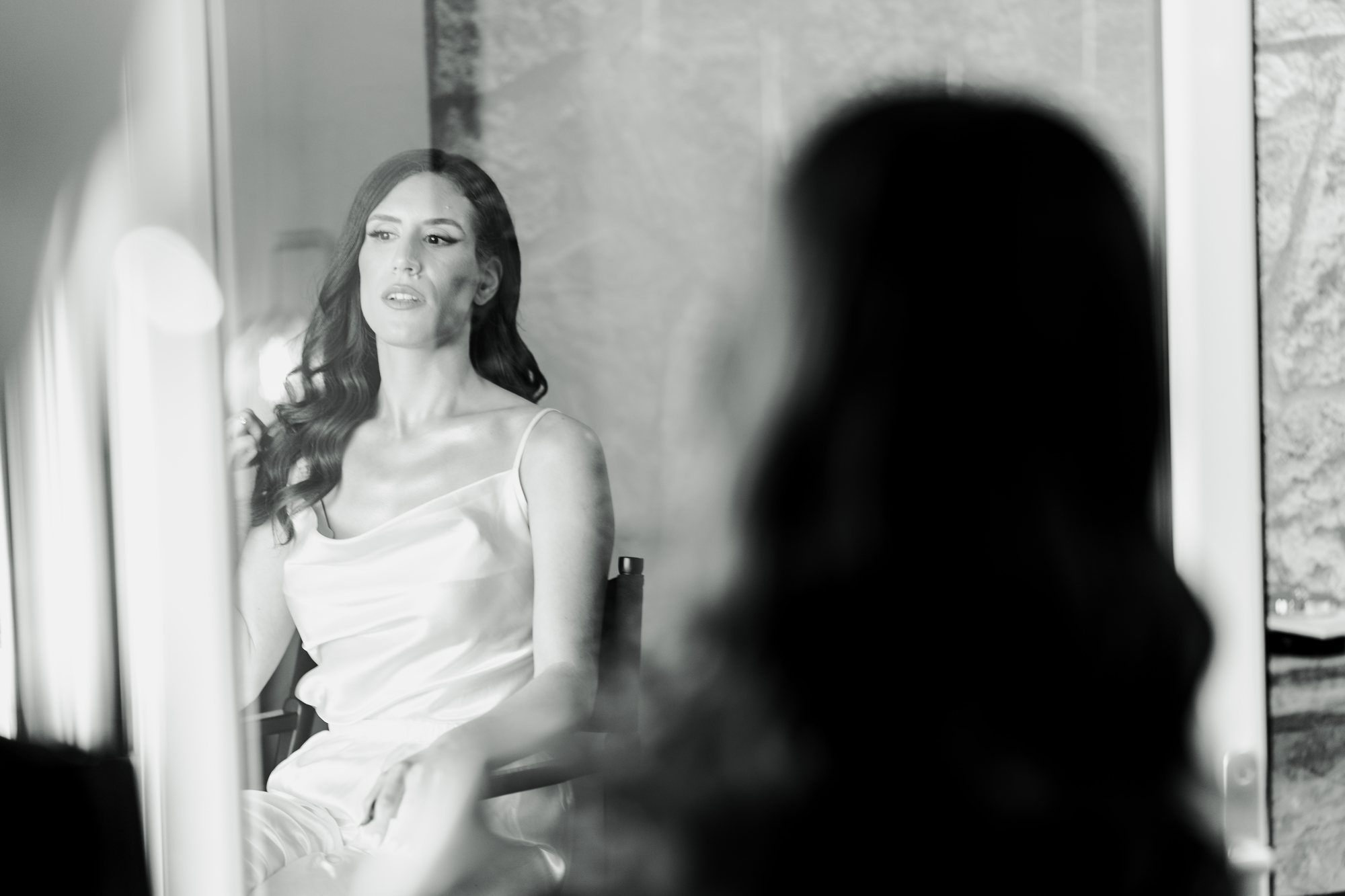 Black and white photo of the bride reflected in a mirror as she waits
