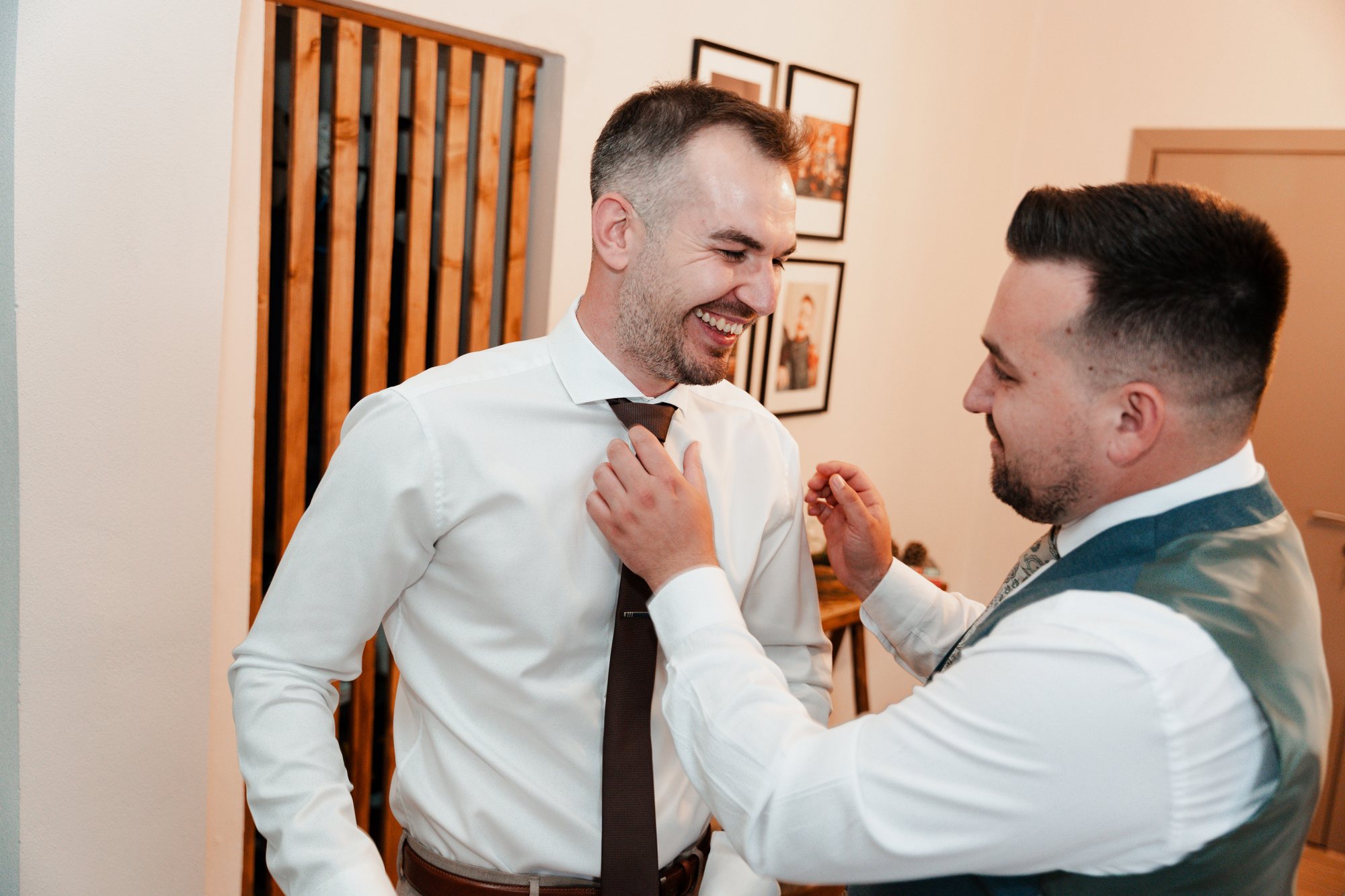 The groom laughs as a friend straightens his tie
